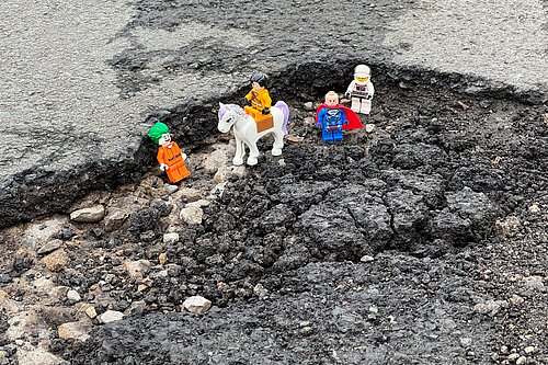 Lego figures placed inside a pothole