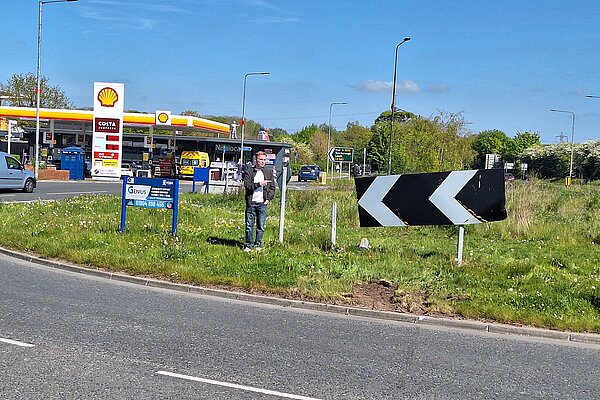 Luke Draper by damaged chevron signs and lamppost on Hull Road roundabout